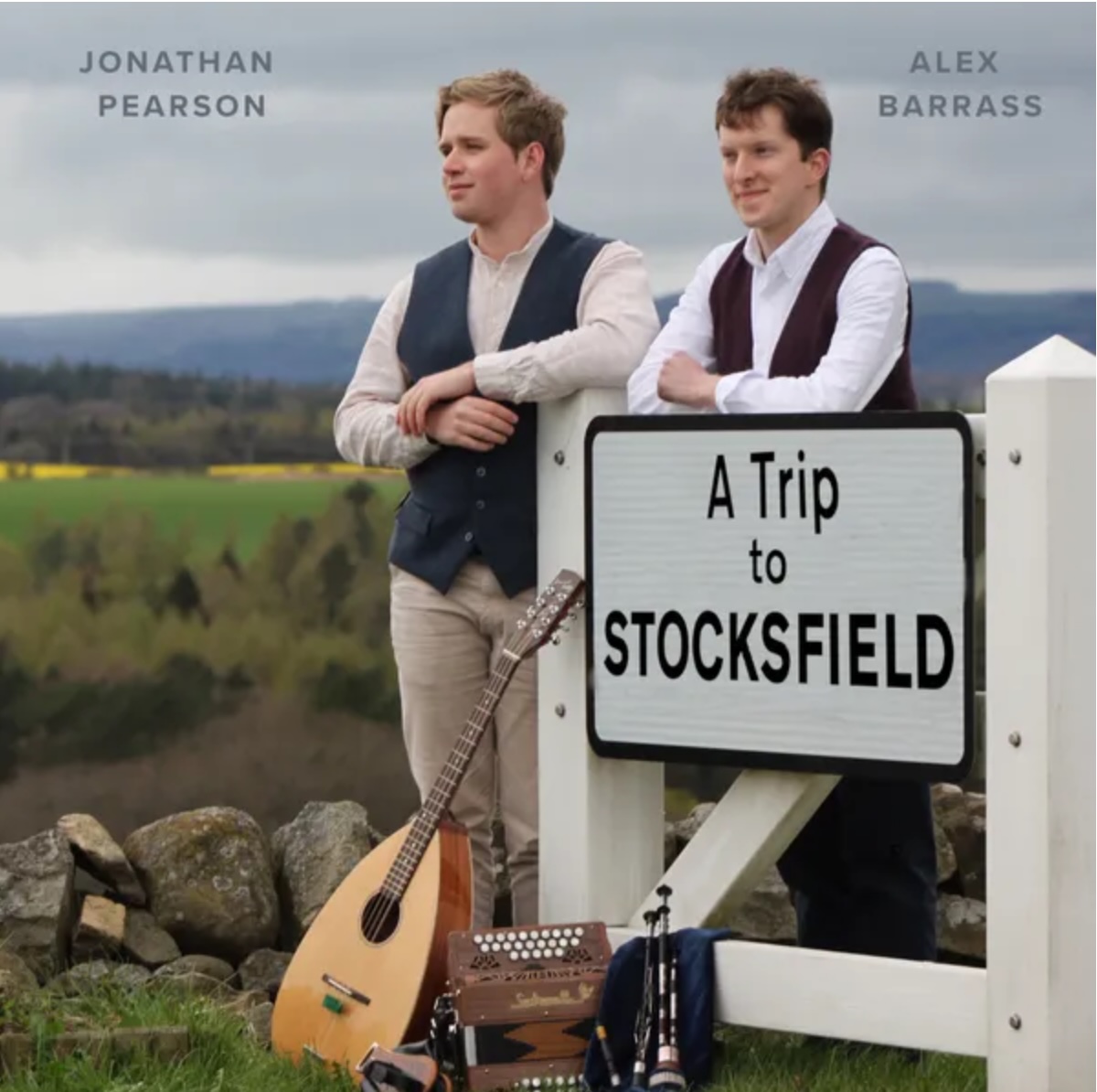 Alex and Jonathan lean against a sign post reading "A Trip to Stocksfield"